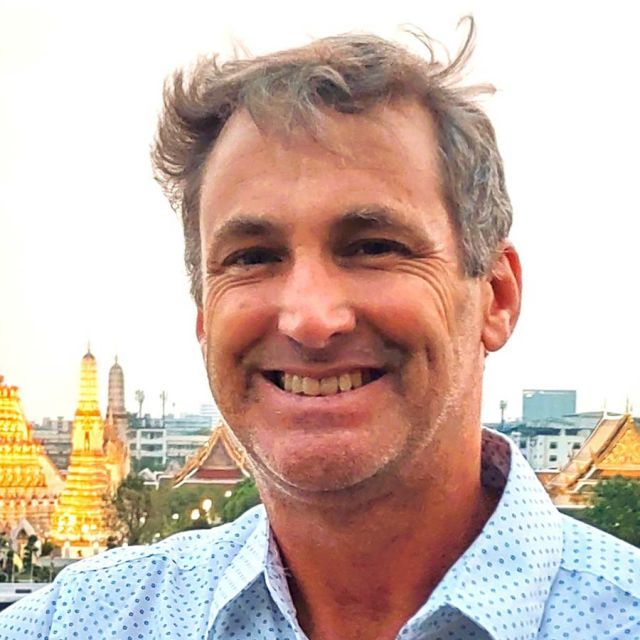 The image shows a man smiling.