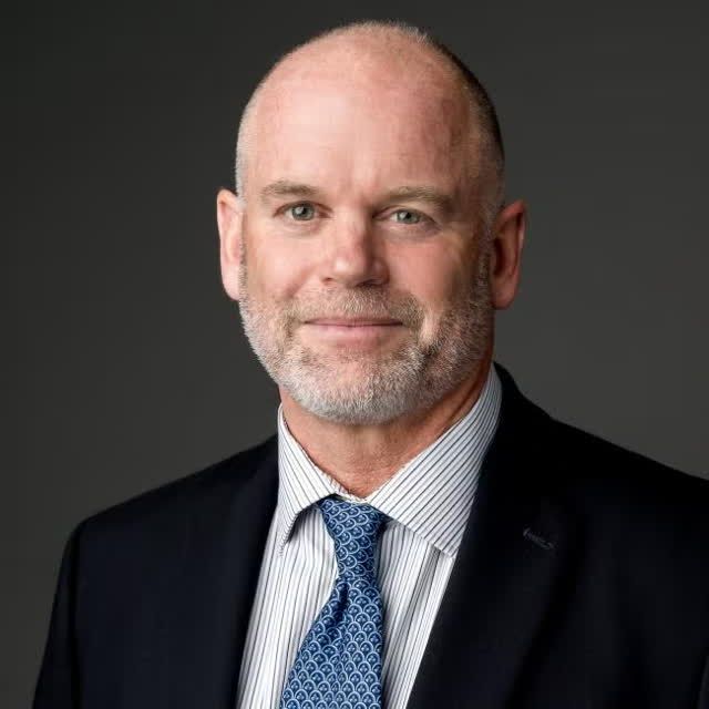 Man wearing suit and tie smiling.