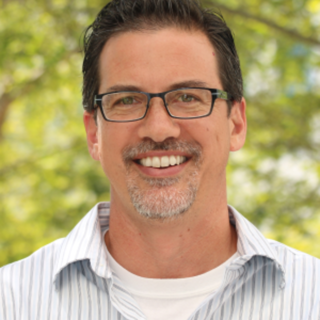 Man with glasses smiling.