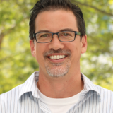 Man with glasses smiling.